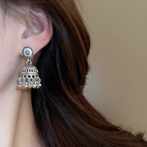 Close-up of vintage silver Jhumka earrings with floral engraving and bell-shaped tassel style
