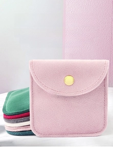 Macro detail of velvet jewelry pouches with snap button closure in multiple soft colors