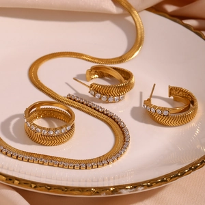 Detail of 18K gold plated jewelry set with V-shaped herringbone pattern and white zircons