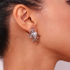 Macro detail of a polished silver spider stud earring on a model earlobe