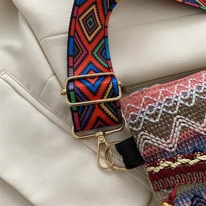 Close-up of woven ethnic shoulder bag with colorful geometric strap and gold hardware