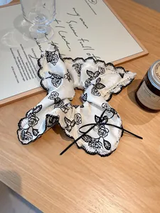 Detail of floral lace hair scrunchie with cream satin rose pattern and pearl bow