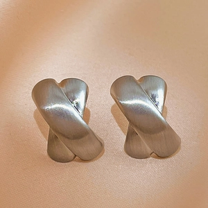 Detailed view of silver X-shaped cross stud earrings with a brushed metal texture