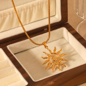 Gold sun pendant necklace with snake chain displayed in a wooden jewelry box