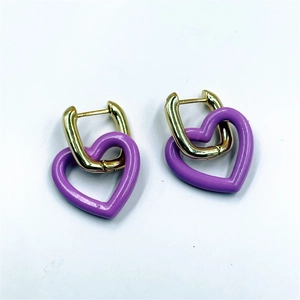 Détail des boucles d'oreilles cœur en émail violet avec crochets dorés sur fond blanc