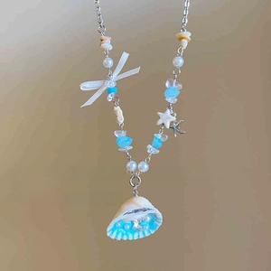 Detail of multi-layer beaded necklace featuring white bow, natural shell and blue stones