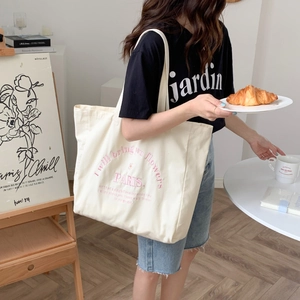 Close-up of large canvas tote bag with pink embroidery in a French romantic studio