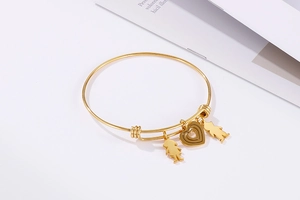 Detail of adjustable gold-plated bangle with heart and family figures charms