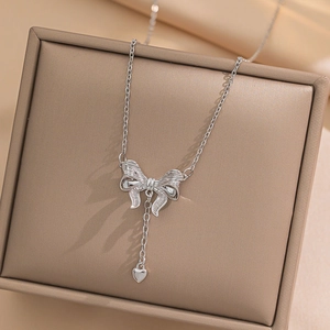 Silver titanium steel necklace with bow and heart pendant on a jewelry display box