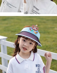 Detail of kids sun visor with cartoon bear and purple UV brim in outdoor setting