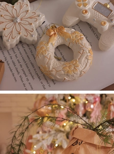Detailed view of cream-colored Christmas ornaments with gold accents and hanging strings