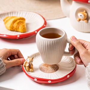 Detail of mushroom-themed ceramic cup with squirrel ornament and red polka dot saucer