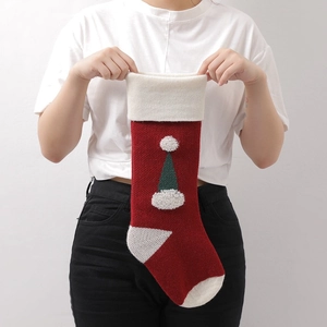 Knitted Christmas stocking with 3D tree pattern held by hands on white background