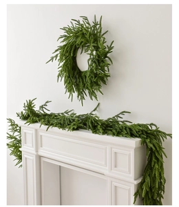 Close-up of fluffy green Norfolk pine garland and wreath on a white fireplace mantle