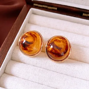 Retro amber resin hoop earrings with gold trim on a premium wooden jewelry display box