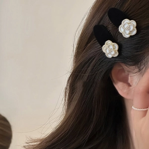Elegant black camellia hair clips with white pearls on dark hair for stylish women