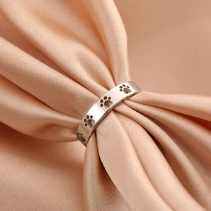 Minimalist stainless steel open ring with cutout cat paw prints on a satin background