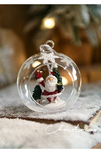 Detail view of a glass Christmas ornament with miniature Santa Claus and tree inside