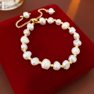 Macro detail of adjustable faux pearl bracelet with gold beads on red velvet jewelry box