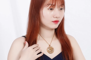 Detail shot of a woman wearing a gold-plated necklace with a round openwork pendant