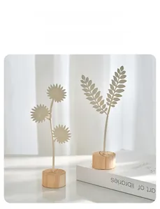 Modern Nordic white metal leaf sculptures with minimalist wooden bases in a bright interior
