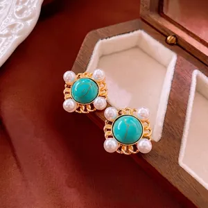 Vintage gold earrings featuring turquoise stones and pearls on elegant silk background