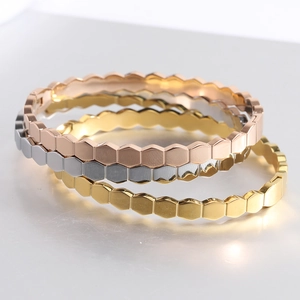 Macro detail of three-color honeycomb geometric bangles in gold, silver and rose gold