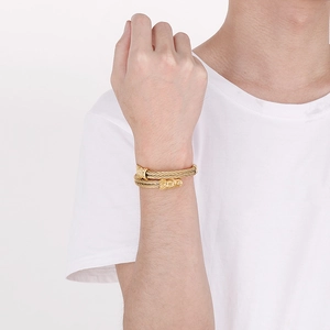 Detail of gold dragon head braided steel cable bracelet on wrist for punk style fashion