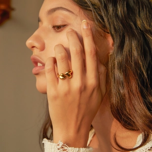 18K gold plated asymmetric heart open ring on model's finger with soft natural lighting