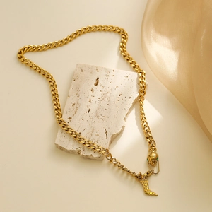 Elegant 18K gold-plated snake necklace with green gemstone eyes on beige stone