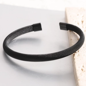 Close-up of black mesh stainless steel C-shaped cuff bracelet with woven texture