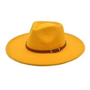 Dettaglio di un cappello fedora giallo a tesa larga con cintura in pelle marrone e fibbia oro