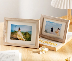 Close-up of a natural wood photo frame with white matting and warm home decor elements