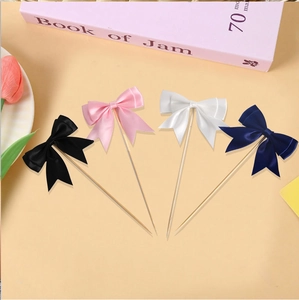 Detail view of four colorful ribbon bow cake toppers in black pink white and navy blue
