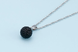 Detail of a silver-plated chain necklace with a black crystal-studded disco ball pendant