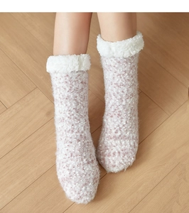 Close-up of pink knit floor socks with white fleece lining on a warm wooden floor