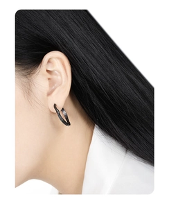 Close-up of S925 silver irregular textured black wave hoop earrings worn by a model