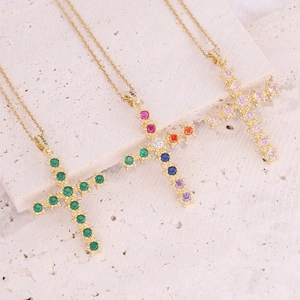 Detail of three 18K gold plated cross pendants with colorful zircon stones on stone base