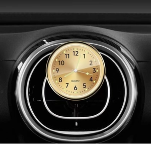 Detailed view of a gold luminous car quartz clock mounted on a dashboard air vent