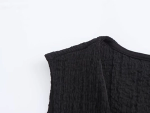 Detail of black textured bubble fabric on sleeveless top with precise stitching and seams