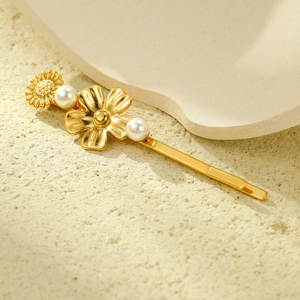 Golden flower hair clip with pearls and metal petals on a minimalist stone surface