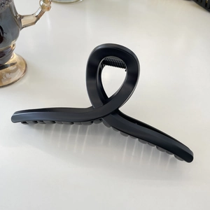 Close-up of a large matte black hair claw clip with minimalist design on a white surface