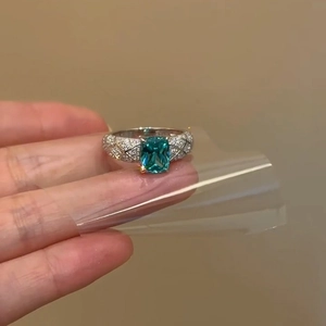 Elegant emerald cut teal gemstone ring with quilted diamond pavé motif in gold