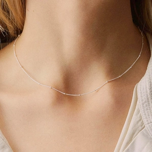 Close-up of a silver beaded chain necklace worn as a minimalist choker for women