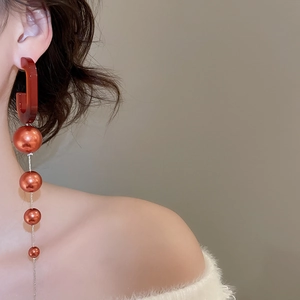 Detail of red-brown gradient beaded drop earrings featuring acrylic semicircles on model