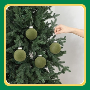 Olive green velvet Christmas ball ornament hanging on a tree being adjusted by hand