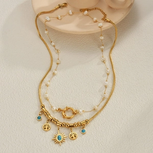Detail der goldenen Schlangenkette mit blauem Sonnenanhänger und Barockperlen-Lagenlook