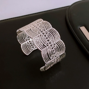 Macro shot of silver vintage open cuff bracelet with layered wave hollow pattern