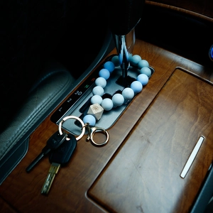 Detail of blue silicone bead keychain with wood butterfly accent on wooden car console
