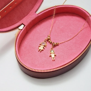 Detail of 18K gold stainless steel boy and girl pendants in a pink jewelry box